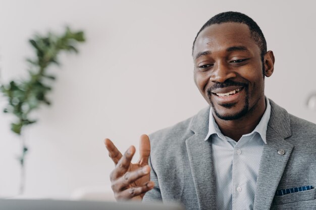 Lächelnder afrikanisch-amerikanischer Geschäftsmann, der einen Videoanruf mit Kunden auf dem Laptop führt, berät Kunden