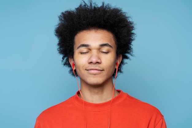 Lächelnder afroamerikanischer Mann mit Kopfhörern, der Musik mit geschlossenen Augen hört. Technologiekonzept