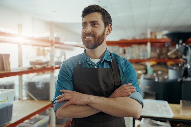 Foto lächelnder arbeiter der kleinen kaffeefabrik in einheitlichem verschwommenem hintergrund