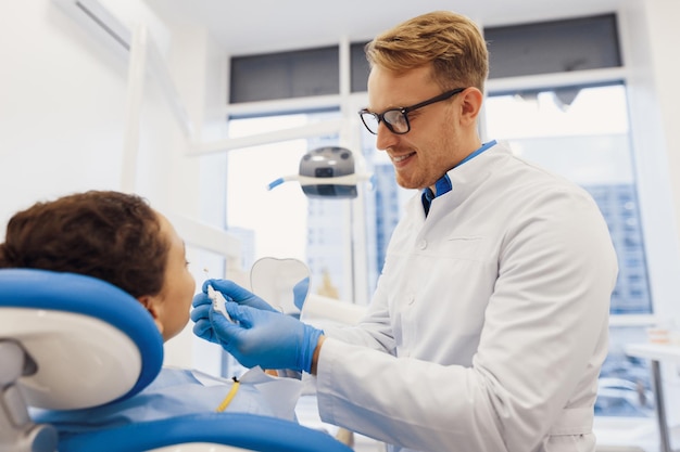 Lächelnder Arzt und Patientin, die Zahnfarbe mit Palette auswählen Medizinischer Behandlungsprozess