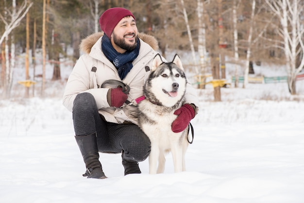 Lächelnder asiatischer Mann mit Hund im Winter