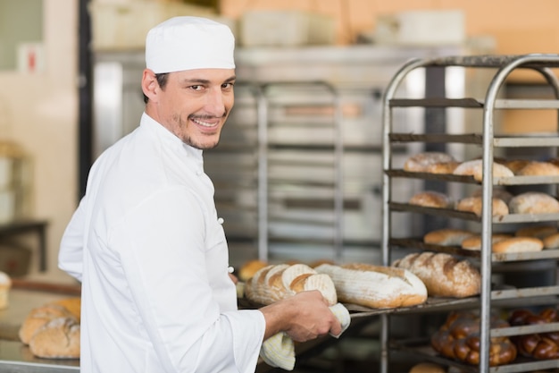 Lächelnder Bäcker, der Behälter brot hält