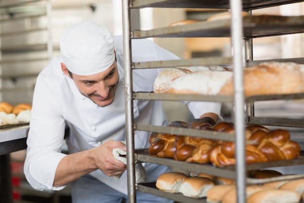 Lächelnder Bäcker, der Behälter des Brotes drückt