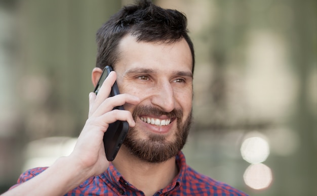 Lächelnder bärtiger Mann, der einen Anruf macht. Glücklicher Mann im modernen Hemd.