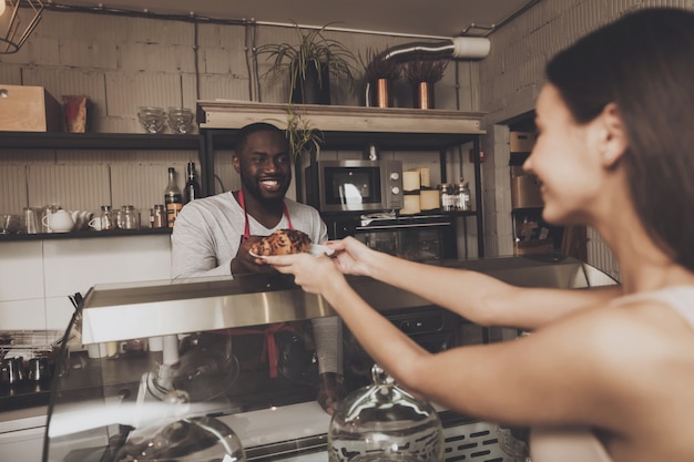 Lächelnder barista mann gibt einem mädchen ihre bestellung