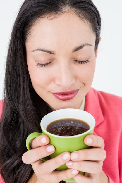 Lächelnder Brunette, der ihren Kaffee riecht