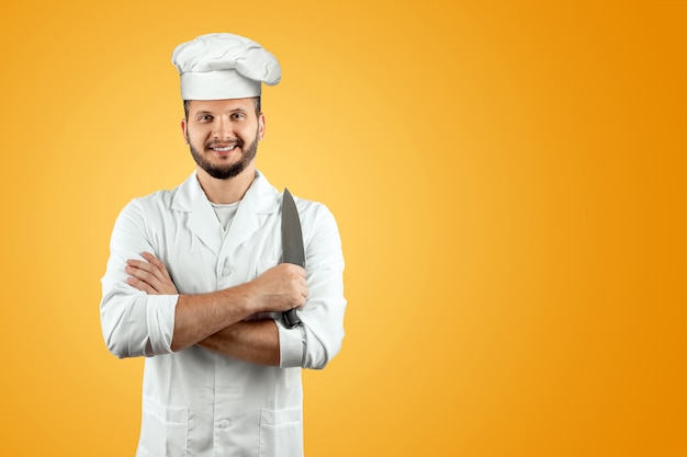 lächelnder Chef in einem Hut, der ein Messer auf einem orange Hintergrund hält