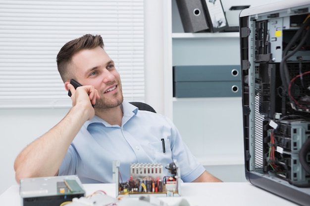 Lächelnder Computertechniker beim Anruf durch offene CPU