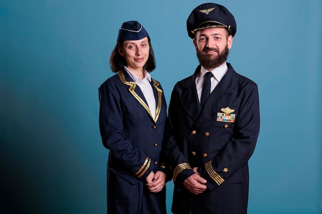 Foto lächelnder flugzeugpilot und flugbegleiter in professionellem, einheitlichem studio-medium-shot-porträt, flugzeugbesatzung, die in die kamera schaut. flugzeugkapitän und stewardess stehend, flugzeugbesatzung