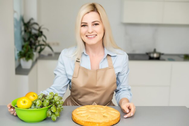 Lächelnder Frauenkoch hält Apfelkuchen.