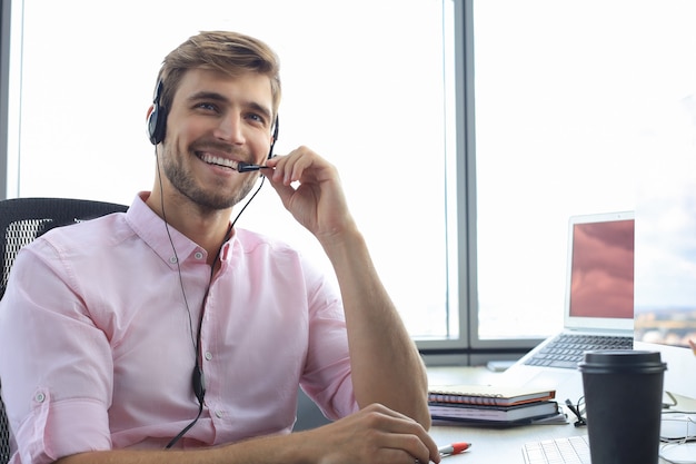 Lächelnder freundlicher hübscher junger männlicher Call-Center-Betreiber.