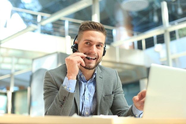 Lächelnder freundlicher hübscher junger männlicher Call-Center-Betreiber.