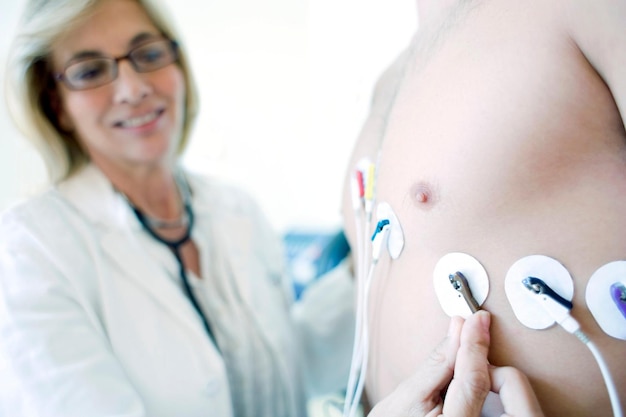 Foto lächelnder, fürsorglicher indischer arzt, der eine alte ältere patientin in einer klinik oder im krankenhaus auf dem bett hält, unterstützt, gesundheitskonzept für ältere menschen