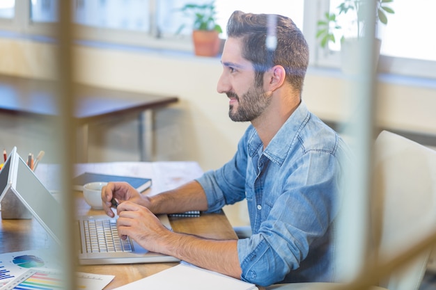 Lächelnder Geschäftsmann, der an Laptop arbeitet