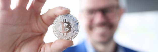 Lächelnder Geschäftsmann, der Bitcoin hält, um Geld mit Bitcoins ohne Investitionskonzept zu verdienen