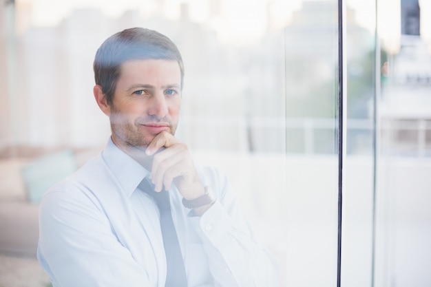 Lächelnder Geschäftsmann, der heraus das Fenster schaut