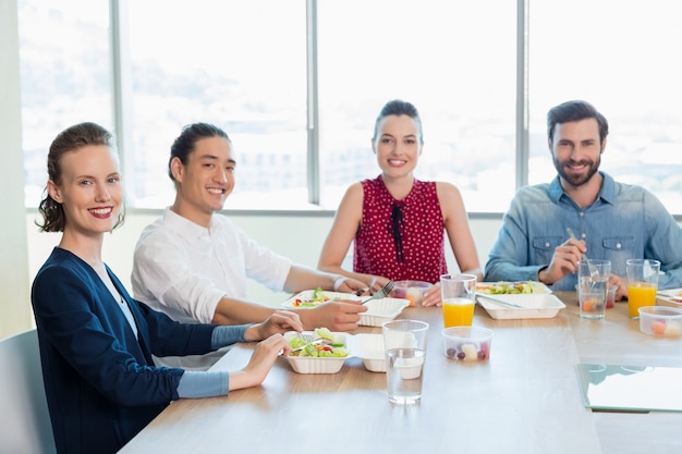 Foto lächelnder geschäftsmann, der mahlzeit im büro hat