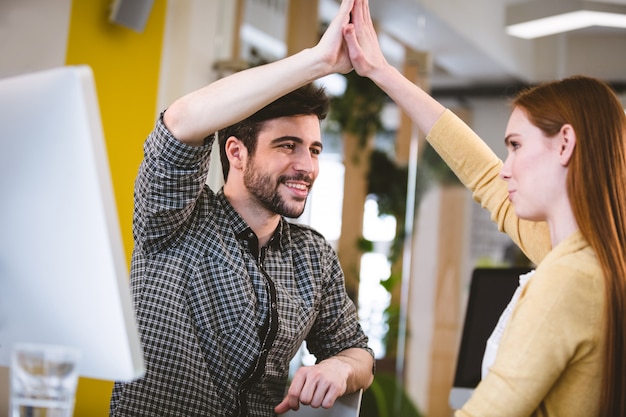 Lächelnder Geschäftsmann, der weiblichen Mitarbeiter High-Five gibt