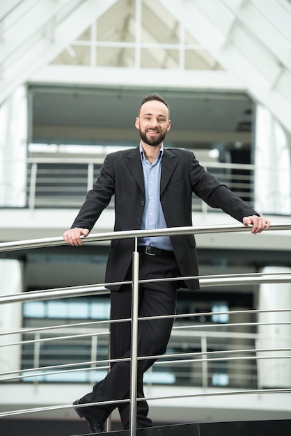 Lächelnder Geschäftsmann im modernen Büro betrachtet Kamera.