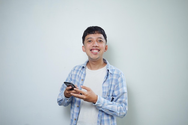 Lächelnder Gesichtsausdruck des asiatischen Mannes unter Verwendung des Handys, das Kamera betrachtet