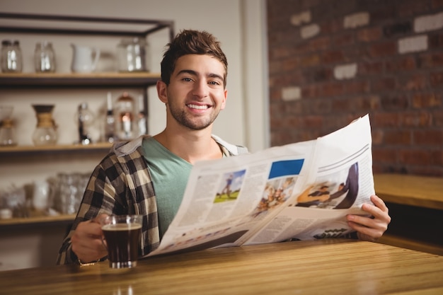 Foto lächelnder hippie, der kaffee trinkt und zeitung liest