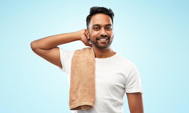 lächelnder indischer Mann mit Handtuch auf blauem Hintergrund