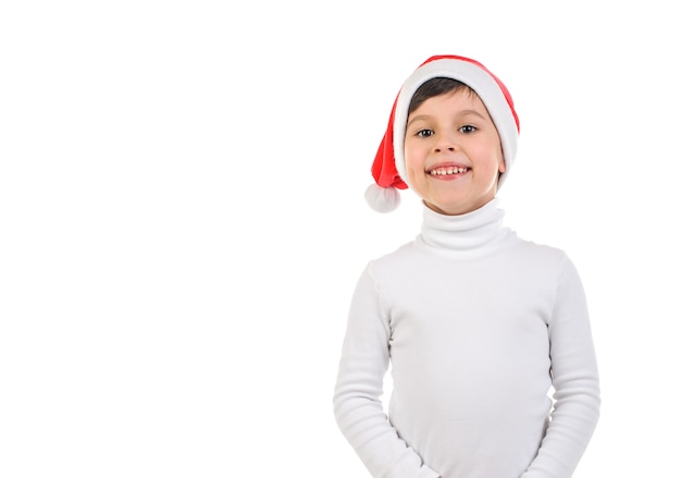Lächelnder Junge 6 Jahre alt in Weihnachtsmann-Hut und weißem Pullover auf weißem isoliertem Hintergrund Neujahr