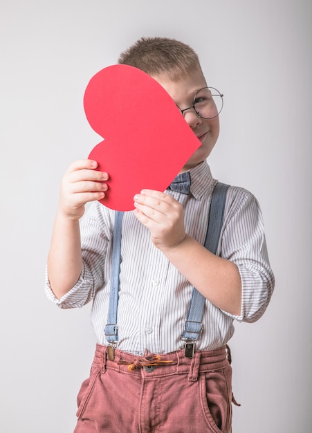 Lächelnder Junge, der ein rotes Herz hält