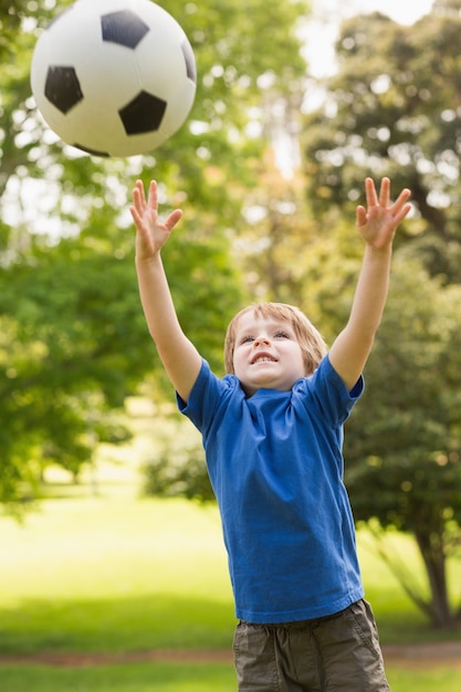 Lächelnder Junge, der mit Ball im Park spielt