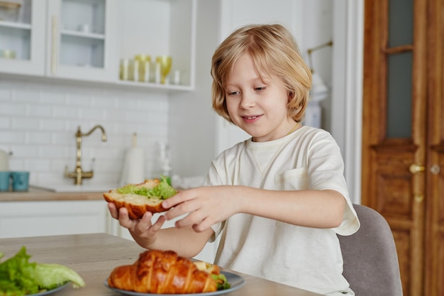 Lächelnder Junge, der zu Hause Sandwich isst