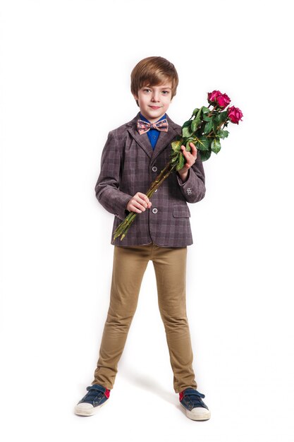 Lächelnder Junge mit einem Blumenstrauß von roten Rosen. Valentinstag, 8. März, Muttertag