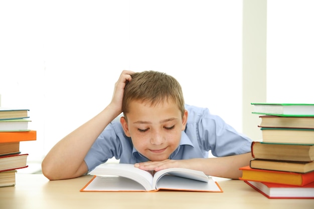 Lächelnder Junge mit vielen Büchern in der Schule