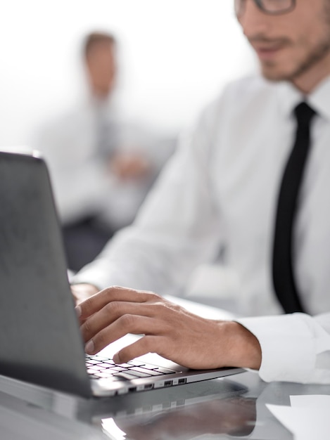 Lächelnder junger Geschäftsmann mit Laptop am Schreibtisch im Büro