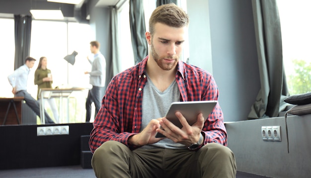 Lächelnder junger Mann mit digitalem Tablet im Büro.