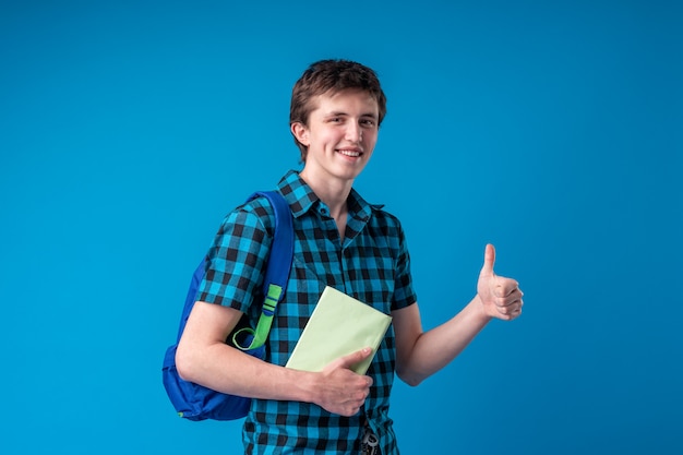 Lächelnder junger Mannstudent in der Freizeitkleidung mit einem Rucksack, der Bücher hält