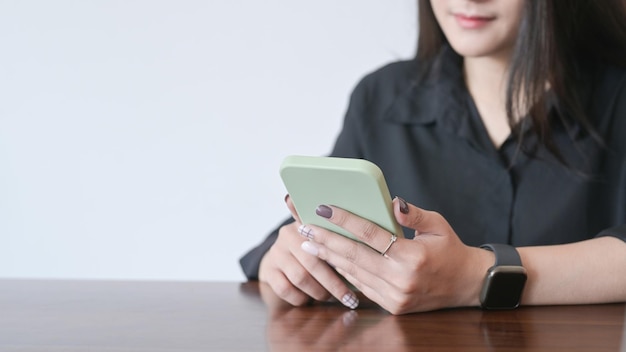 Lächelnder junger weiblicher Büroangestellter, der Handy verwendet