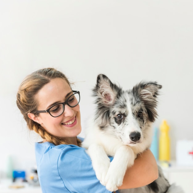 Foto lächelnder junger weiblicher tierarzt mit hund in der klinik