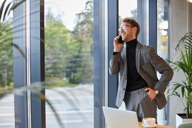 Lächelnder kaukasischer Geschäftsmann erklärt Partnern oder Investoren per Telefon eine neue Geschäftsstrategie