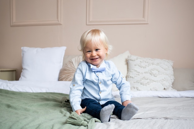 Lächelnder kleiner Junge, der auf Bett liegt. Menschen, Kinder, Ruhe- und Komfortkonzept.