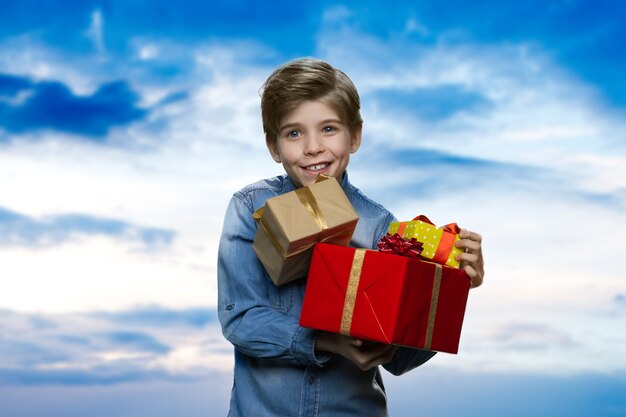 Lächelnder kleiner Junge hält einen Stapel Geschenke