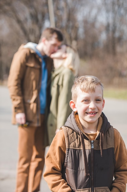 Foto lächelnder kleiner junge vorne, der die eltern im hintergrund küsst