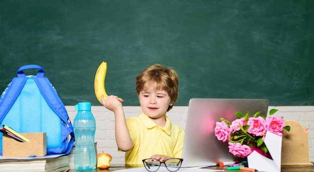 Lächelnder kleiner Schüler, der Spaß gegen den kleinen Jungen der Tafel hat, der bereit ist, zuerst zurück zur Schule zu lernen?