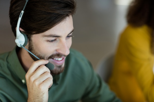 Lächelnder kundendienstmitarbeiter, der über kopfhörer im büro spricht