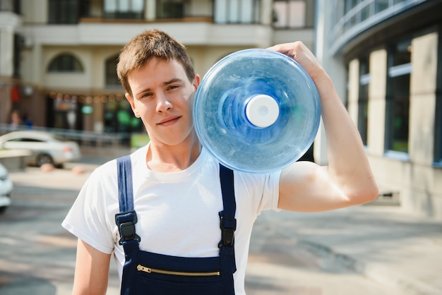 Lächelnder Lieferbote, der eine Wasserflasche auf der Schulter trägt