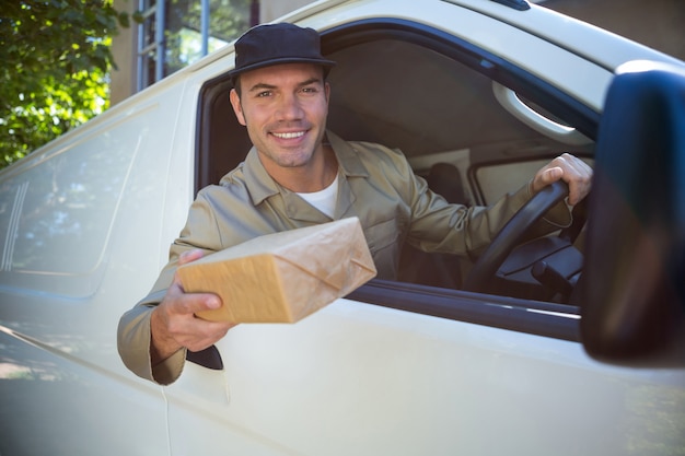 Lächelnder Lieferbote, der in seinem Packwagen sitzt