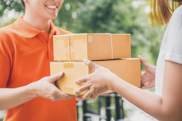 Lächelnder Lieferbote, der Paket an eine Frau liefert