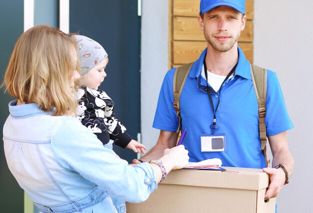 Lächelnder Lieferbote in blauer Uniform, der Paketbox an das Kurierdienstkonzept des Empfängers liefert Lächelnder Lieferbote in blauer Uniform