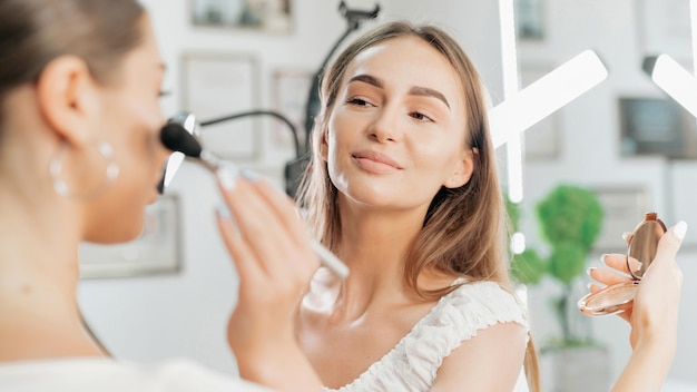 Lächelnder Make-up-Meister macht Make-up für einen Kunden. Hautbemalung