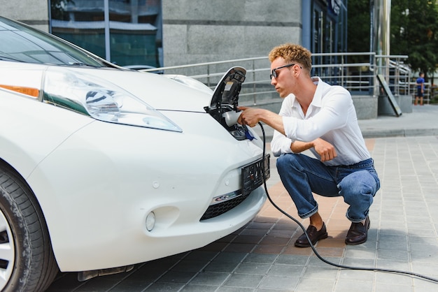 Lächelnder Mann, der das Ladegerät vom Auto trennt