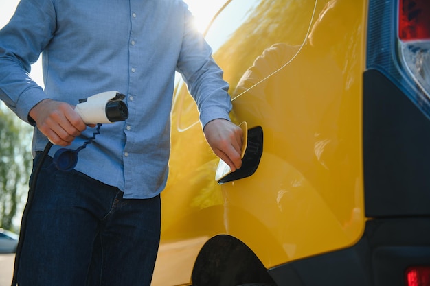 Lächelnder Mann, der das Ladegerät vom Auto trennt